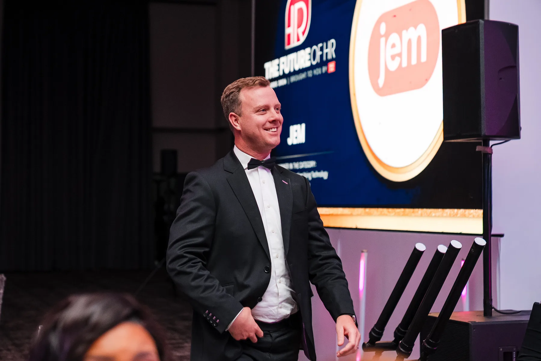 Christopher Hellmann at the Future of HR Awards ceremony beside a screen displaying the Jem logo