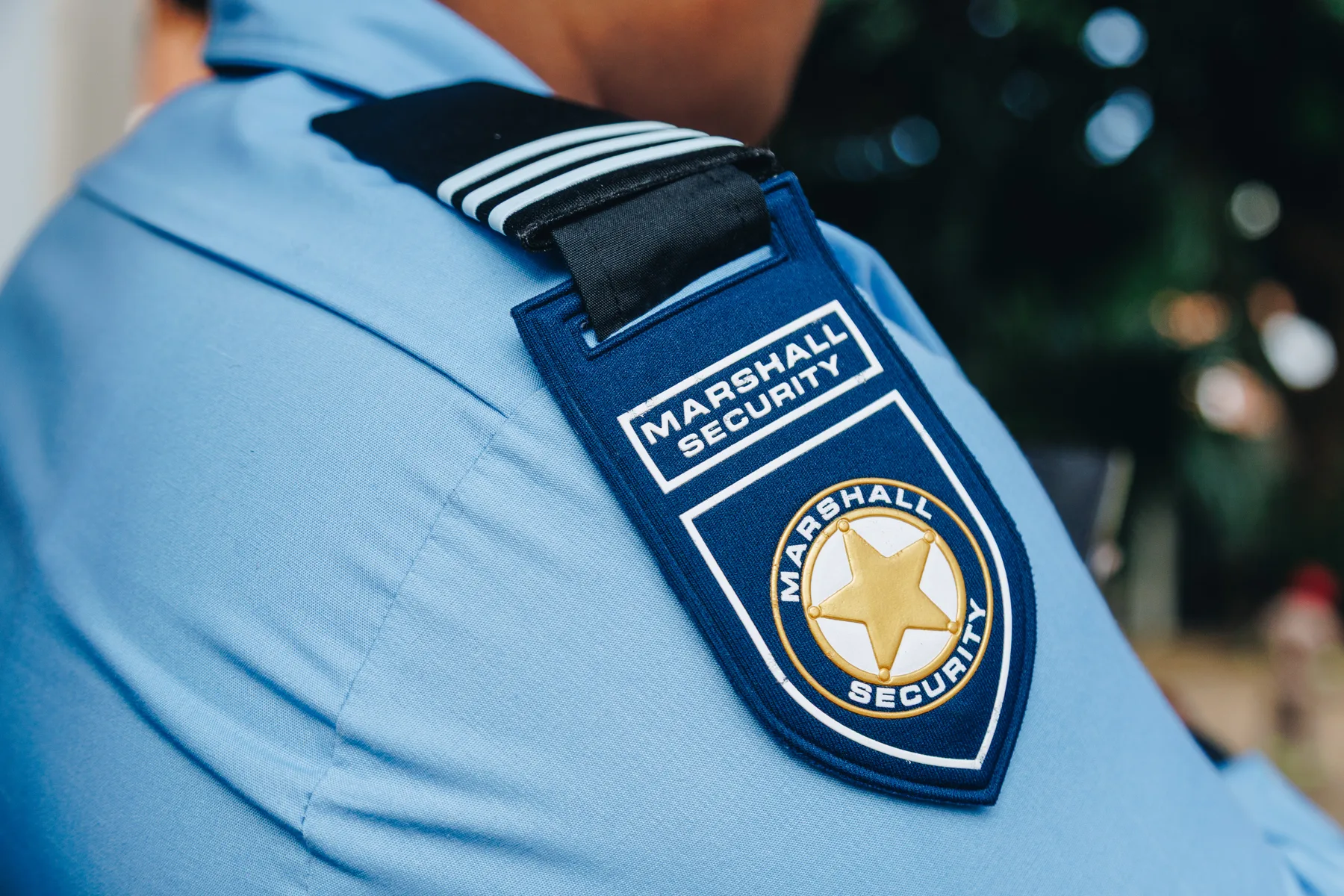 Marshall Security badge and striped epaulette on a blue security officer uniform