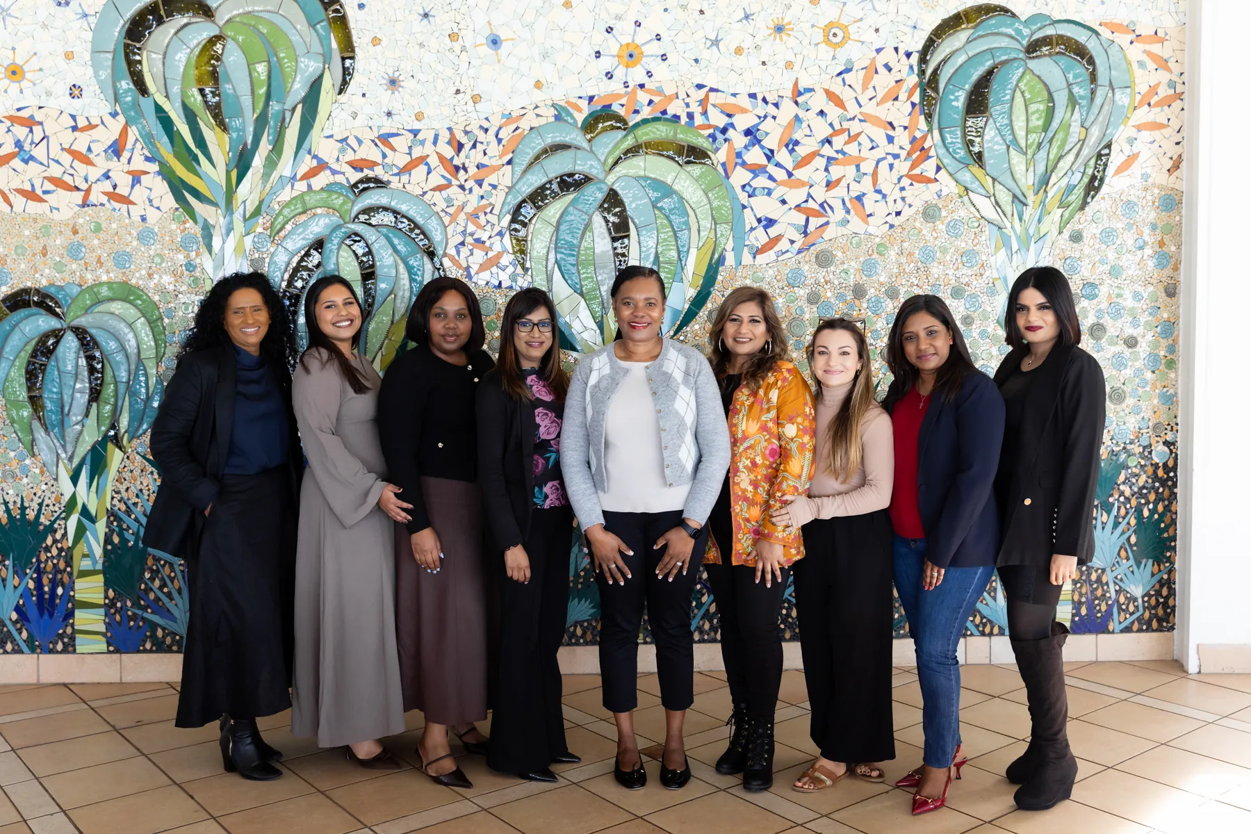 Nine guests at She Leads posed in a row in front of the hotel’s palm-tree mosaic mural.