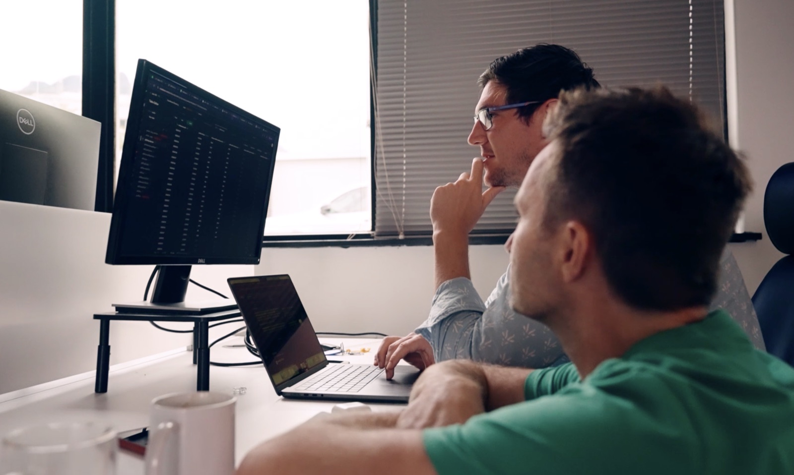 Two Jem engineers looking at code on a monitor and talking it through