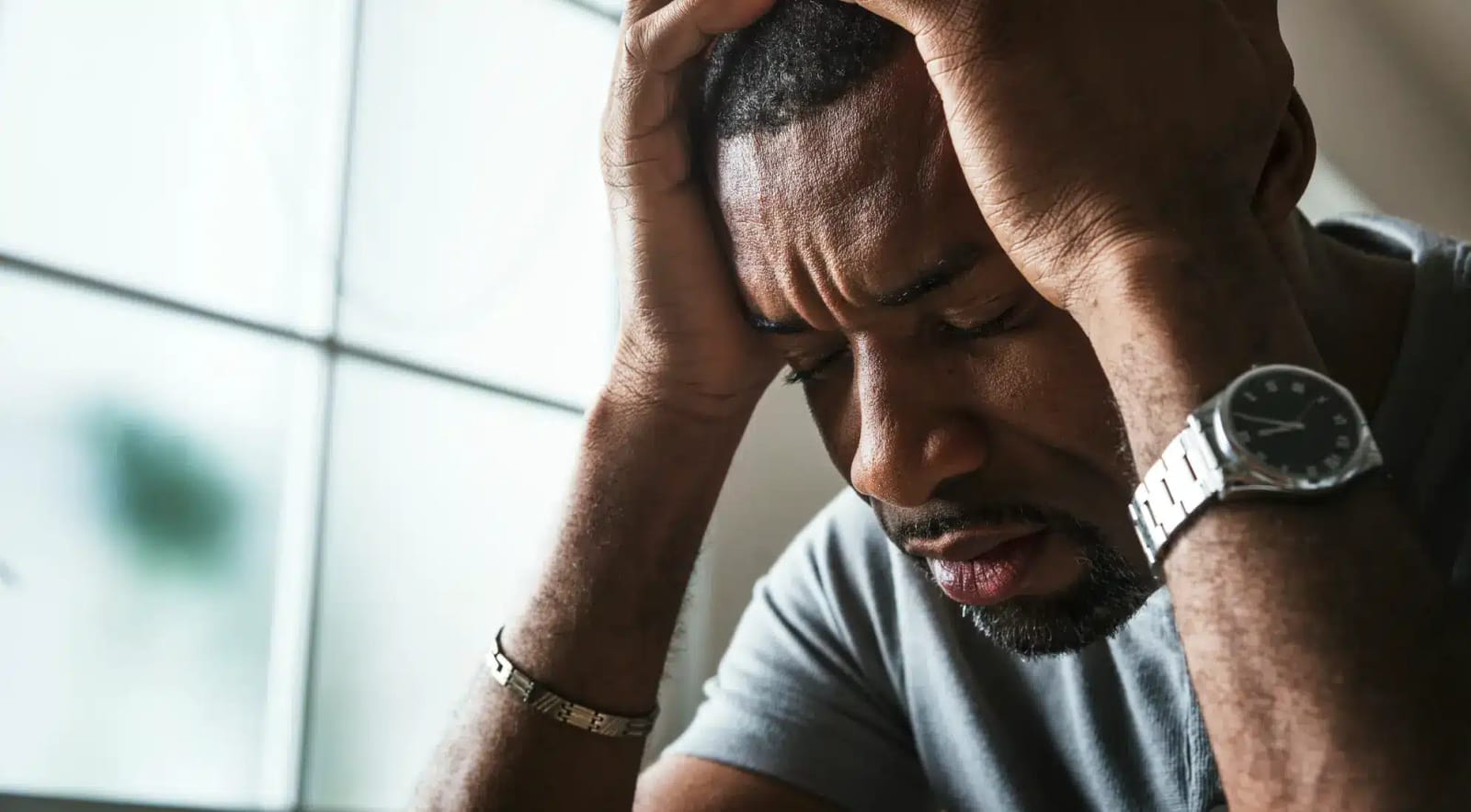 A man sitting with his head in his hand, looking exhausted