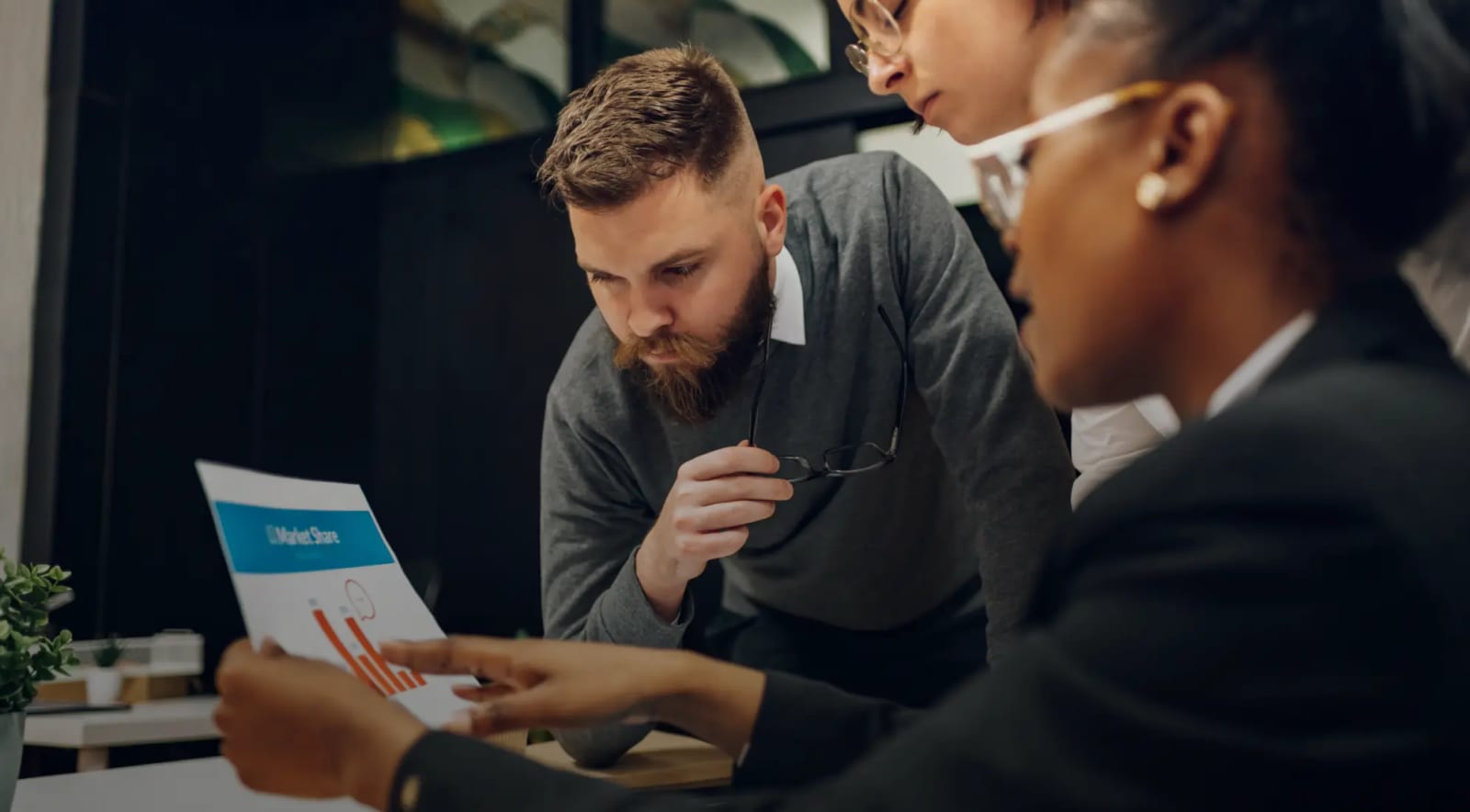 Two people in a meeting reading over a printed document together