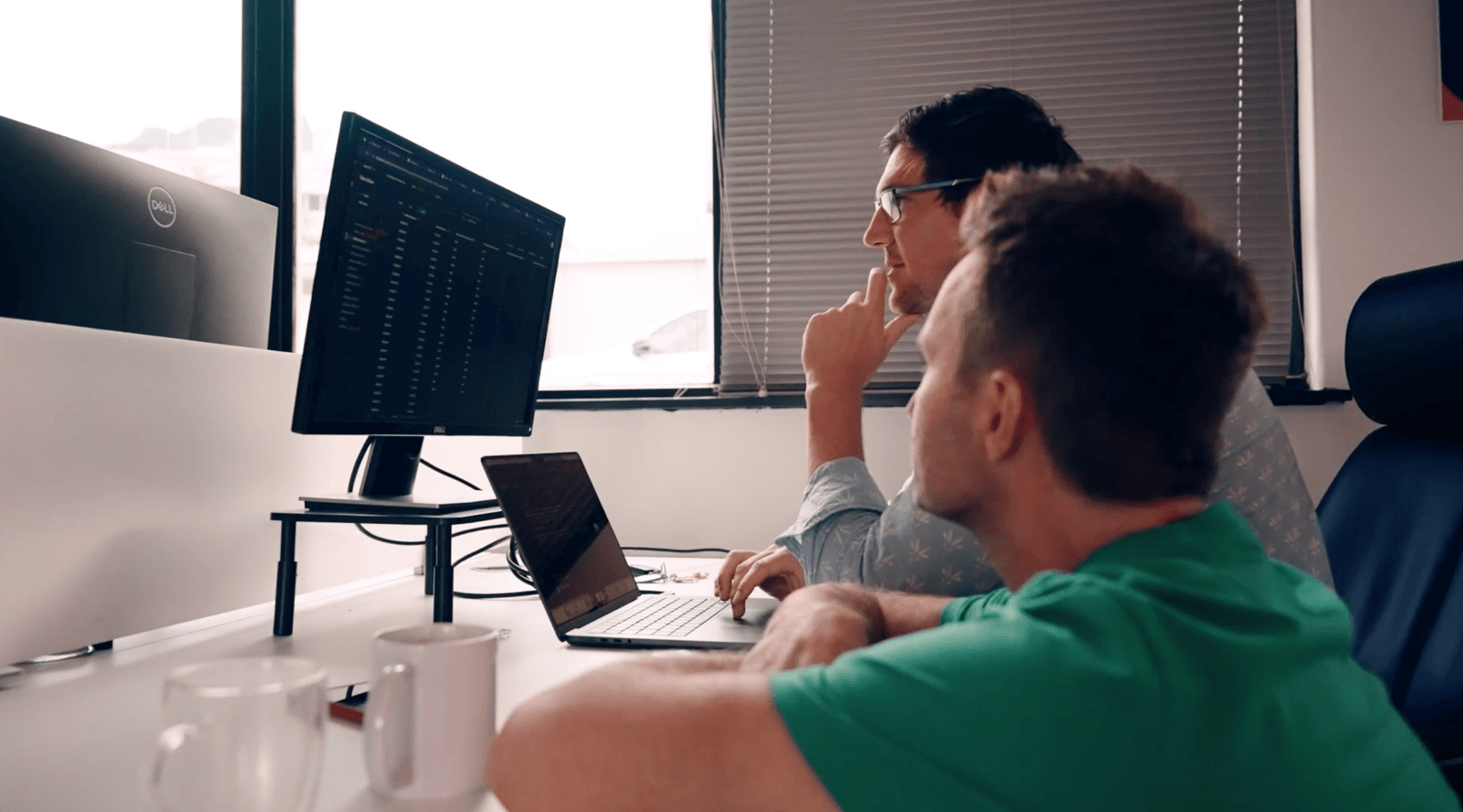 Two Jem engineers at a desk studying a dashboard on a monitor