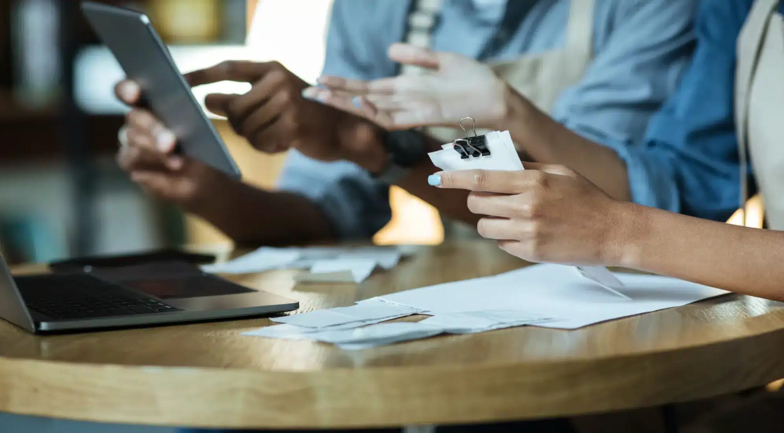 Two people at a table going through paperwork, one holding a tablet and the other a clipped bundle of documents
