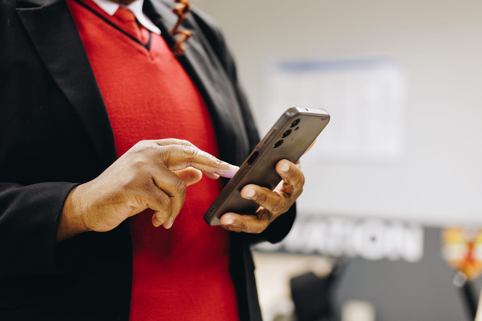A security officer in uniform using a smartphone, close on their hands